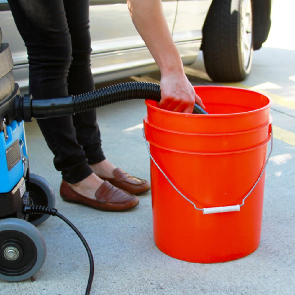 Person using a vacuum cleaner with an orange bucket outdoors