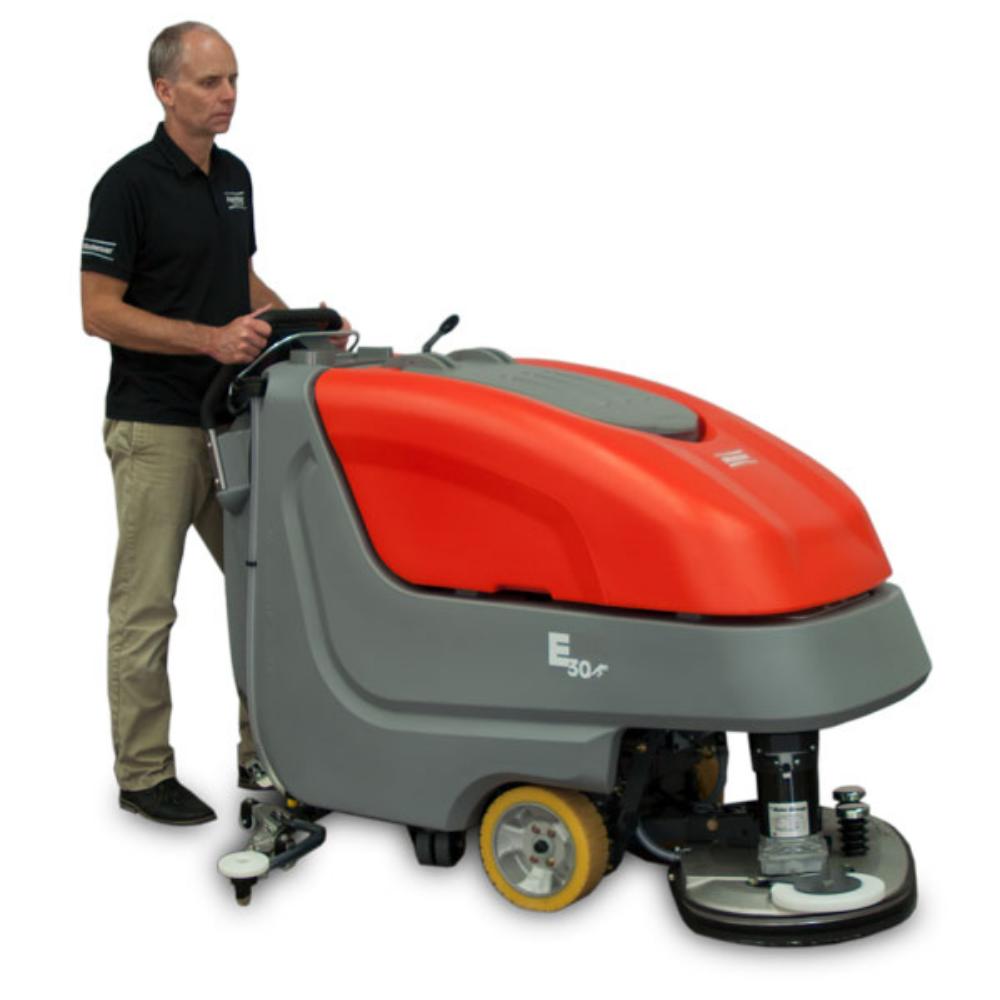 Man with black polo and khaki pants pushing powerboss e3030 medium sized floor scrubber. 