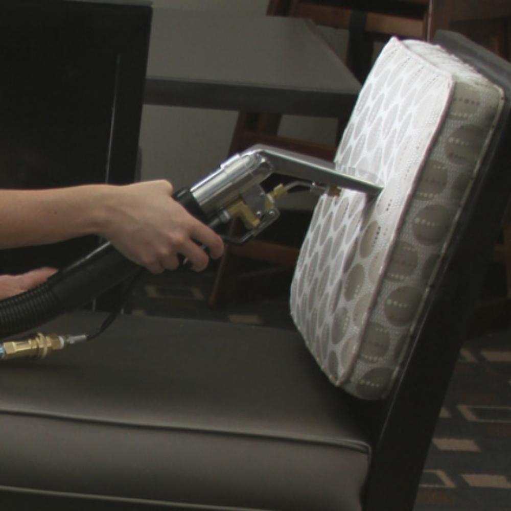Person using a vacuum wand cleaner on a seat.