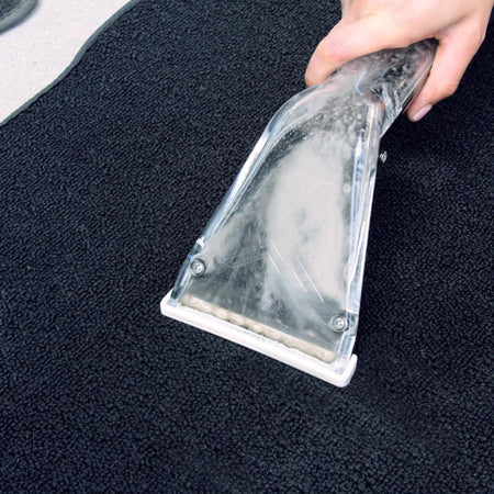 Person cleaning a black car mat with a Mytee S 300 H Tool.