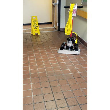 Floor cleaning equipment with a yellow caution sign on a tiled floor.
