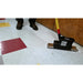 Person using a mop on a tiled floor with a wooden wall in the background